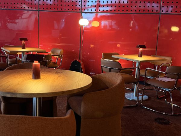Mesa de NUBEL con luz cálida junto a la pared roja